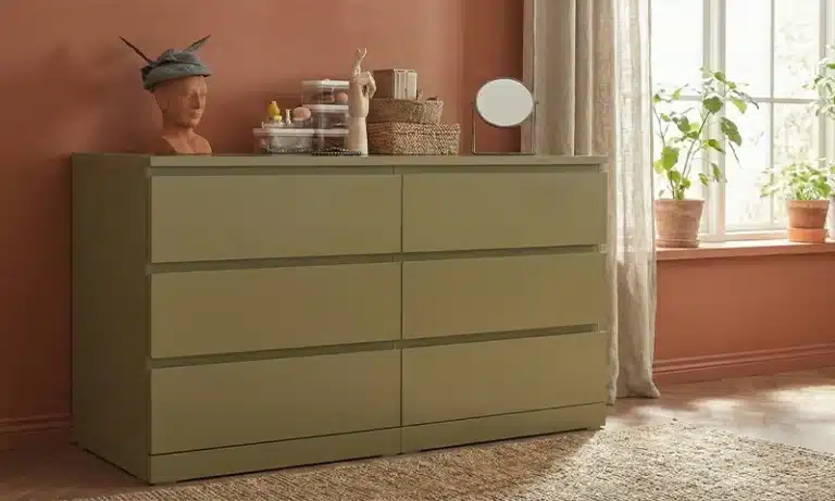 Een groen geschilderde IKEA kast in een woonkamer met een terracotta kleur op de muur.